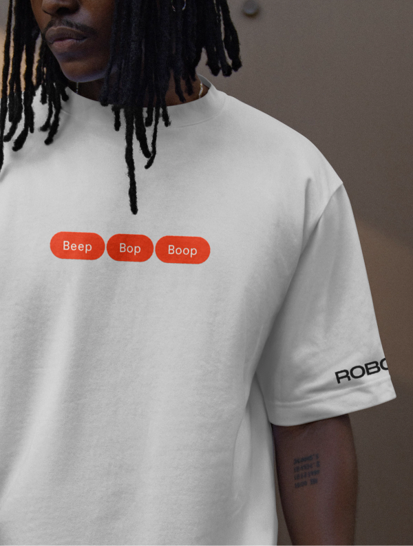 A man in a t-shirt with three orange pill-shaped shapes containing the words "beep, bop, boop" and a ROBOTS logo on the sleeve