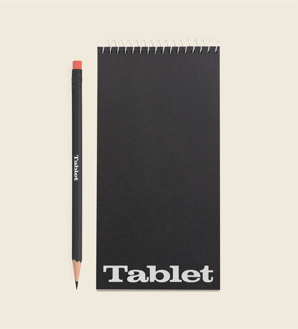 A back journalist notebook with a white Tablet logo on the bottom, next to a black pencil with a white Tablet logo in the middle