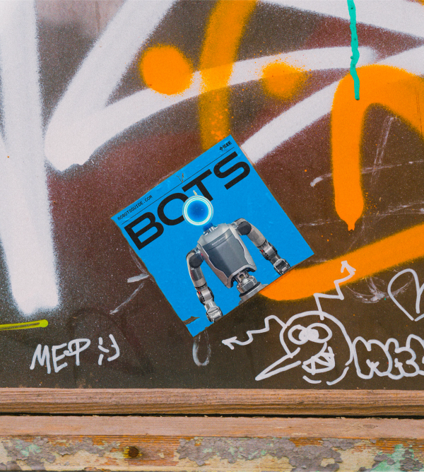 A blue sticker featuring a portrait of a humanoid robot is shown on a wall covered in graffiti 